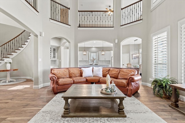 living area with baseboards, arched walkways, and wood finished floors