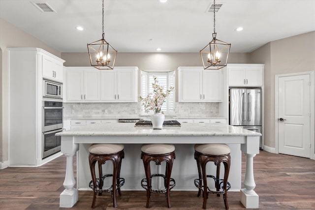 kitchen with a notable chandelier, a kitchen island, visible vents, and stainless steel appliances