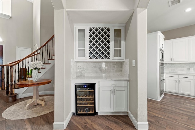 bar featuring wine cooler, stairway, stainless steel appliances, a bar, and dark wood-style flooring