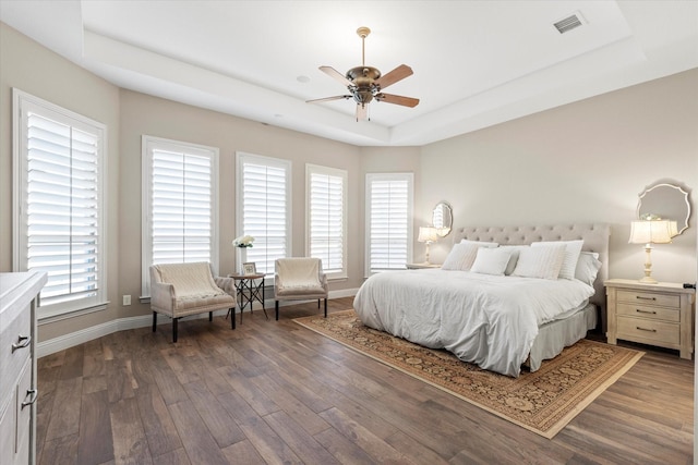 bedroom featuring visible vents, baseboards, a tray ceiling, and dark wood-style flooring