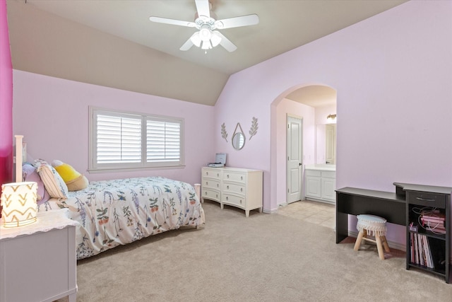 bedroom with ensuite bathroom, arched walkways, light colored carpet, ceiling fan, and vaulted ceiling