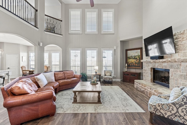 living area featuring a wealth of natural light, arched walkways, a ceiling fan, and wood finished floors