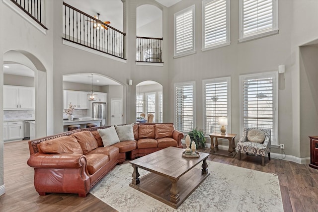 living room featuring baseboards, arched walkways, and wood finished floors