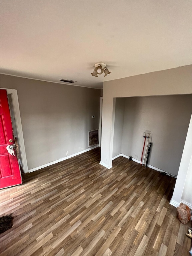 unfurnished living room featuring visible vents, baseboards, and wood finished floors