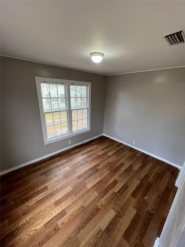 empty room featuring visible vents, baseboards, and dark wood-style floors