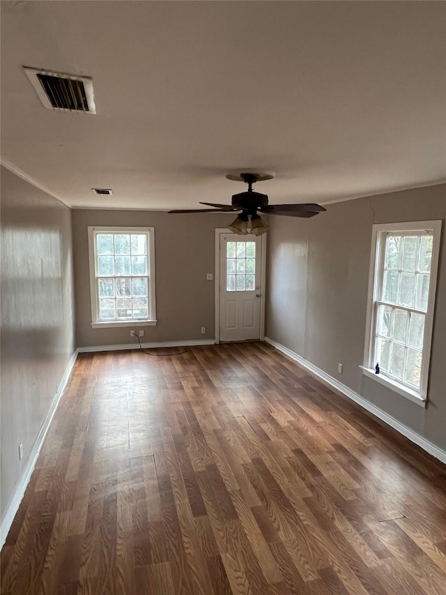 unfurnished room featuring baseboards, a ceiling fan, dark wood-style flooring, and visible vents