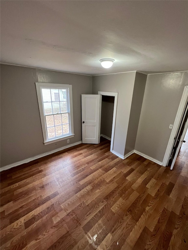 empty room featuring baseboards and dark wood finished floors