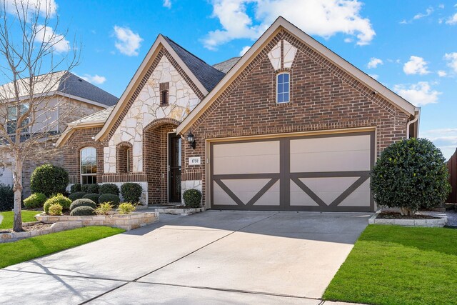 view of front of home with driveway, stone siding, a garage, and brick siding