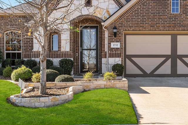 view of exterior entry with a garage, concrete driveway, and brick siding