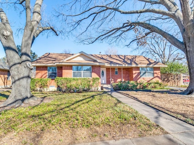 ranch-style home featuring brick siding, a front yard, and fence