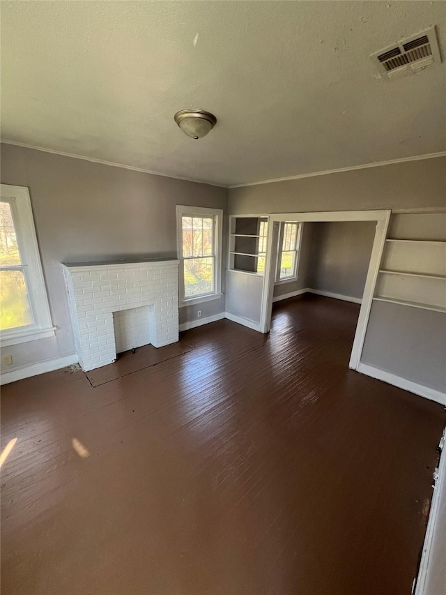 unfurnished living room with visible vents, baseboards, a brick fireplace, and dark wood-style floors