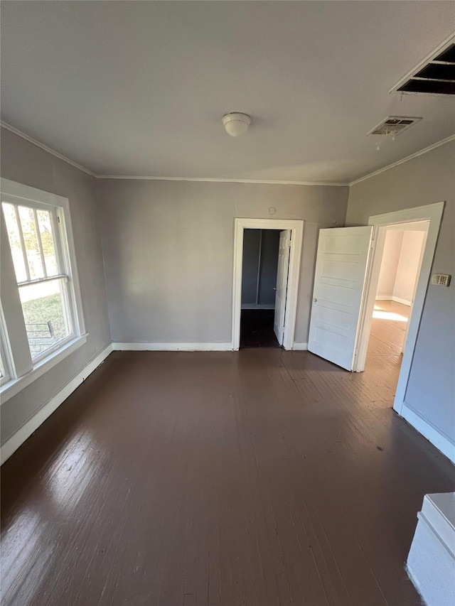 unfurnished bedroom with baseboards, ornamental molding, visible vents, and hardwood / wood-style flooring