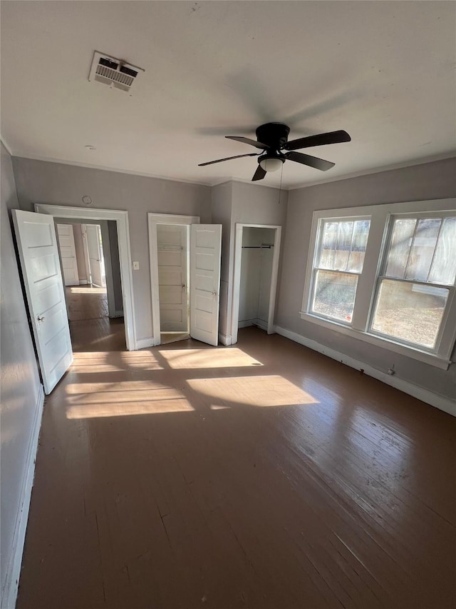 unfurnished bedroom with baseboards, wood-type flooring, a ceiling fan, and visible vents