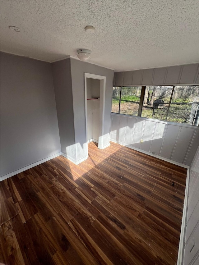 empty room featuring baseboards, a textured ceiling, and wood finished floors