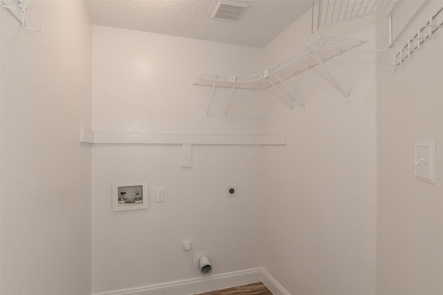 laundry area featuring a textured ceiling, hookup for a washing machine, hookup for an electric dryer, laundry area, and visible vents