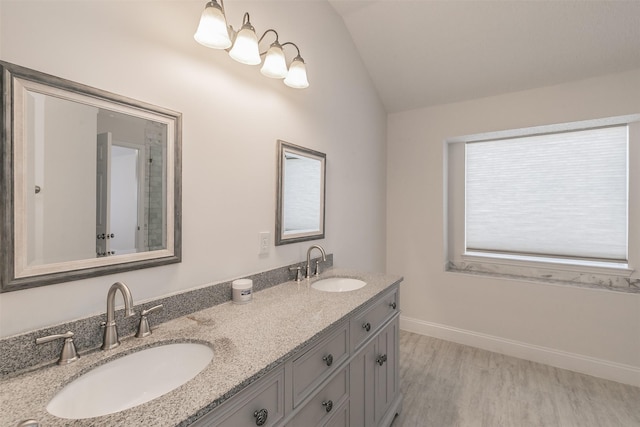 bathroom with vaulted ceiling, double vanity, a sink, and wood finished floors