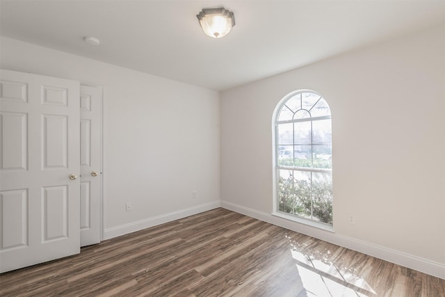 unfurnished room with dark wood-style flooring and baseboards