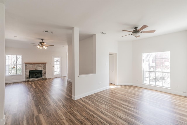 unfurnished living room with a ceiling fan, wood finished floors, visible vents, and a healthy amount of sunlight