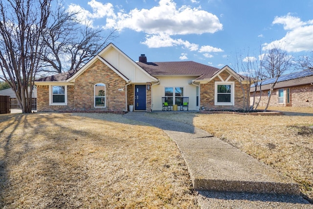 view of front of property with a shingled roof, a chimney, fence, a front lawn, and brick siding