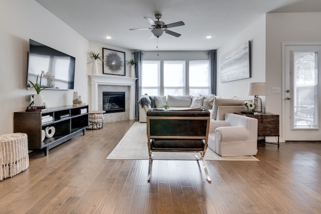 living area featuring a ceiling fan, recessed lighting, a glass covered fireplace, and wood finished floors