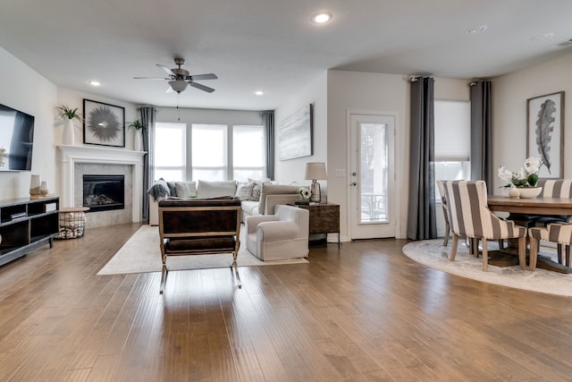 living area featuring a ceiling fan, a glass covered fireplace, recessed lighting, and wood finished floors