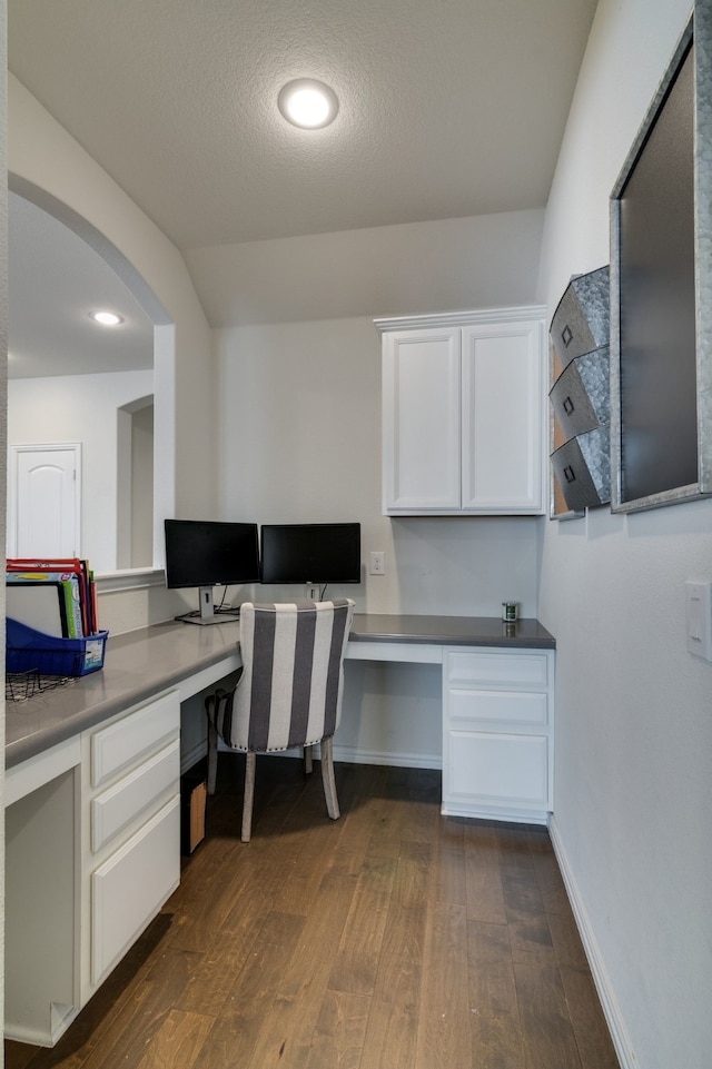 office area with dark wood finished floors, built in desk, and baseboards