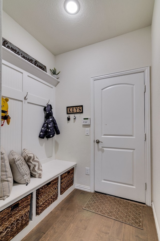 mudroom featuring a textured ceiling, baseboards, and wood finished floors