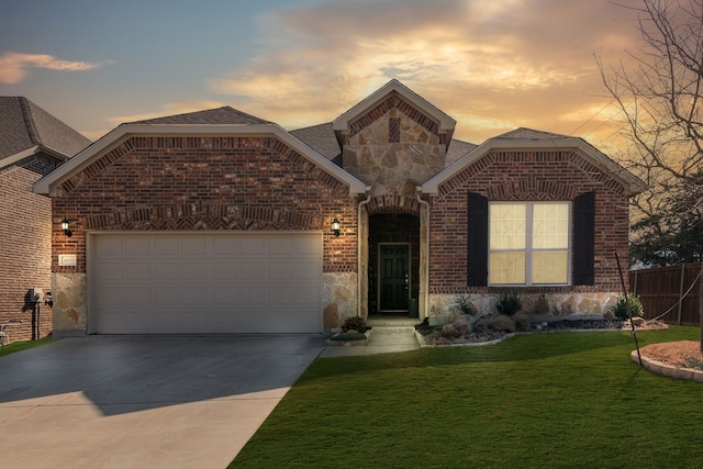 french country home with a garage, concrete driveway, stone siding, a front lawn, and brick siding