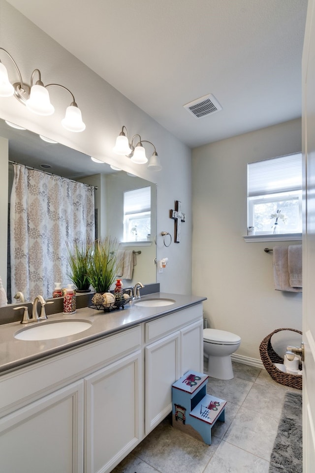 bathroom featuring toilet, a wealth of natural light, a sink, and visible vents