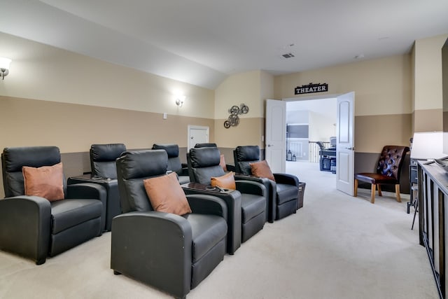 home theater room featuring light carpet, vaulted ceiling, and visible vents