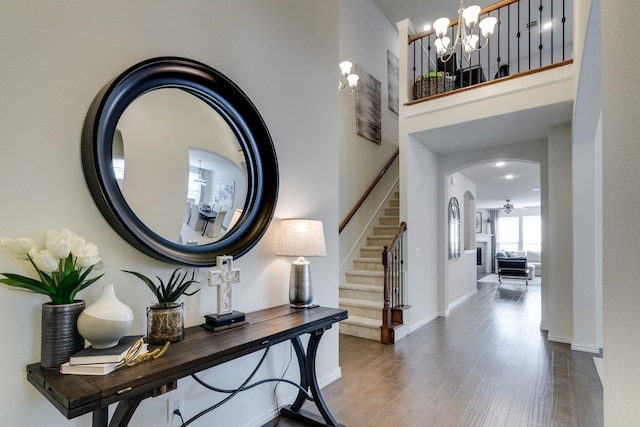 foyer entrance featuring arched walkways, a high ceiling, wood finished floors, baseboards, and stairs