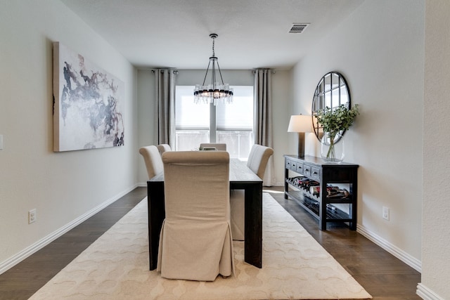 dining room with an inviting chandelier, baseboards, visible vents, and dark wood-type flooring