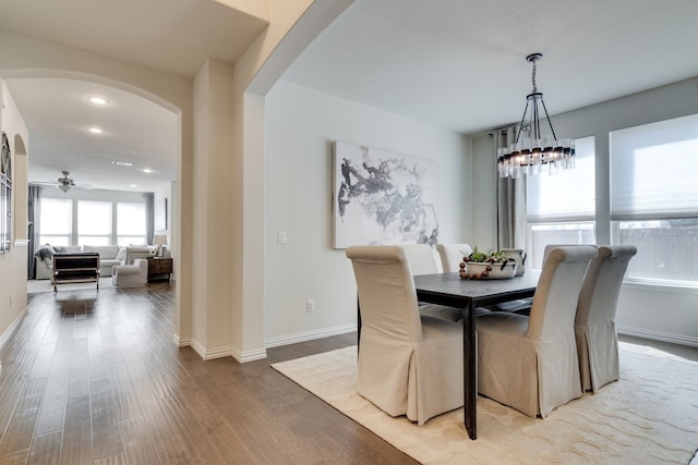 dining area with arched walkways, recessed lighting, ceiling fan with notable chandelier, wood finished floors, and baseboards