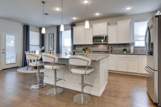 kitchen featuring a healthy amount of sunlight, appliances with stainless steel finishes, backsplash, and dark wood-style flooring