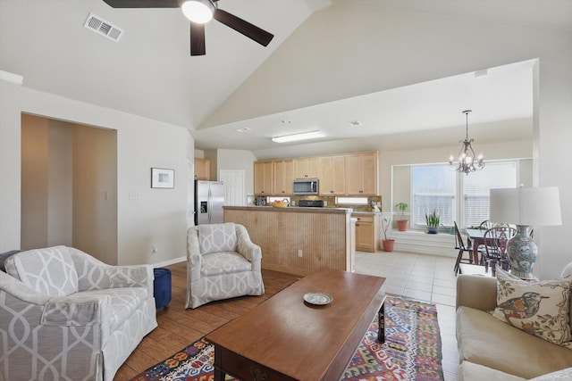 living room featuring light wood finished floors, visible vents, high vaulted ceiling, baseboards, and ceiling fan with notable chandelier