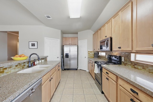 kitchen with light tile patterned floors, decorative backsplash, light brown cabinetry, appliances with stainless steel finishes, and a sink