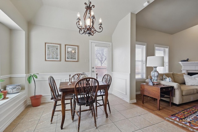 dining room with wainscoting, light tile patterned flooring, and a notable chandelier