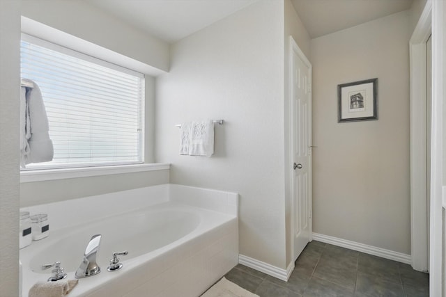 bathroom with tile patterned floors, baseboards, and a bath