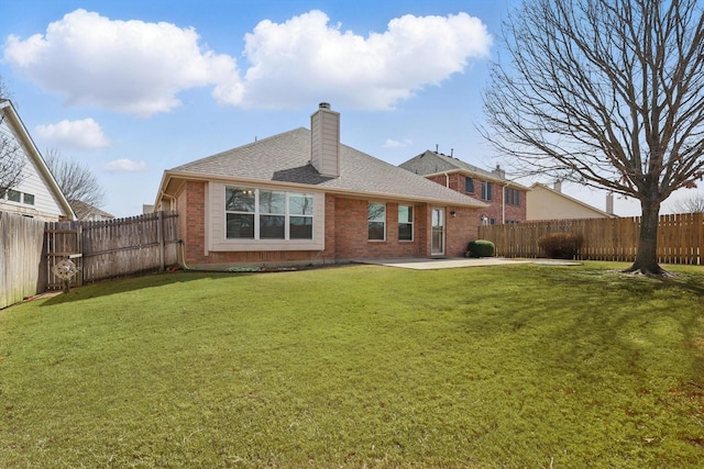 rear view of house featuring a fenced backyard, brick siding, a yard, a chimney, and a patio area