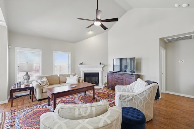 living area with baseboards, visible vents, wood finished floors, and a glass covered fireplace