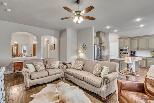 living room featuring baseboards, arched walkways, ceiling fan, wood finished floors, and recessed lighting