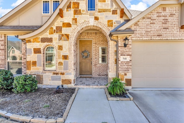 entrance to property with stone siding, brick siding, and an attached garage