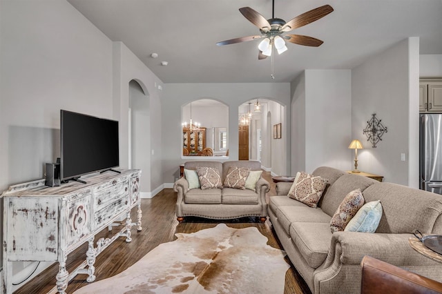 living area with arched walkways, wood finished floors, a ceiling fan, and baseboards