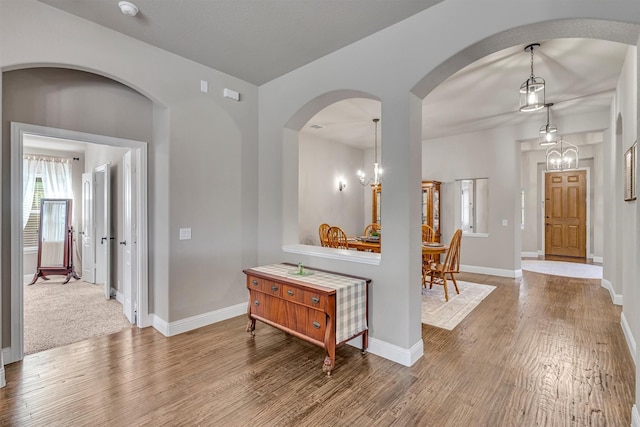 interior space with baseboards, a notable chandelier, and wood finished floors