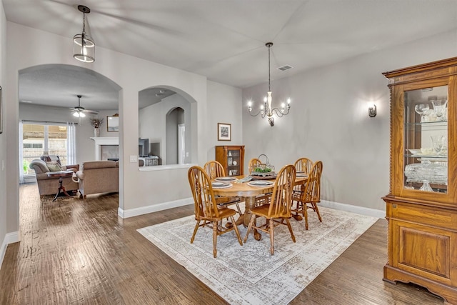 dining room featuring arched walkways, dark wood-style flooring, visible vents, and baseboards