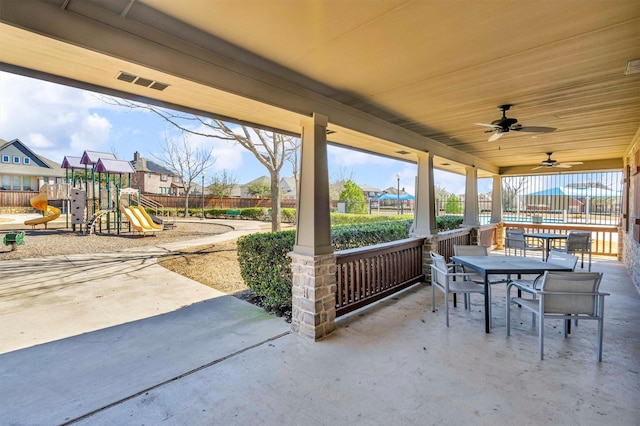 view of patio with a ceiling fan, outdoor dining space, playground community, and fence