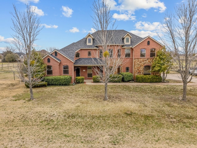 view of front facade featuring stone siding, brick siding, and a front yard