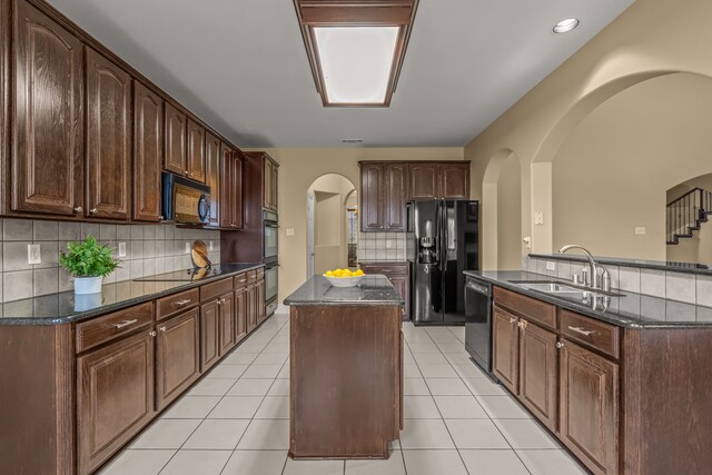 kitchen with a sink, black appliances, light tile patterned floors, and a kitchen island