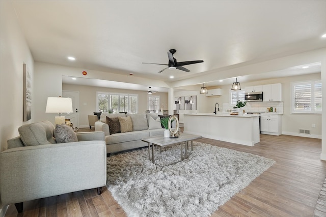 living room with recessed lighting, visible vents, ceiling fan, light wood-type flooring, and baseboards