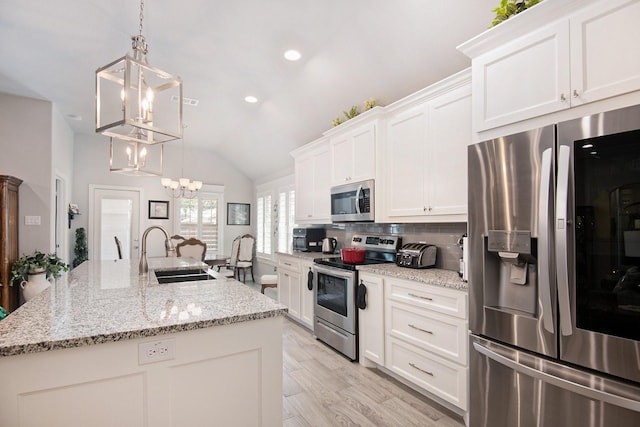 kitchen with appliances with stainless steel finishes, a sink, an inviting chandelier, a kitchen island with sink, and backsplash